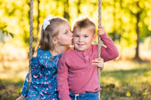 girl kissing boy on swing