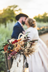 Bride and groom kissing behind floral arrangement