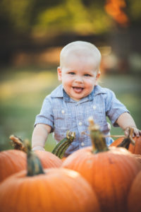 boy standing over pumpkins