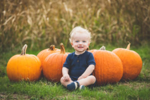 Boy sitting in front of pumpkins