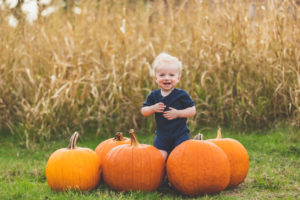 boy standing behind pumpkins
