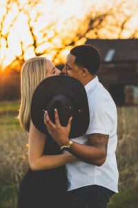 Man and woman kissing behind hat