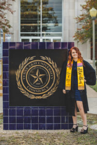 Girl in front of college sign